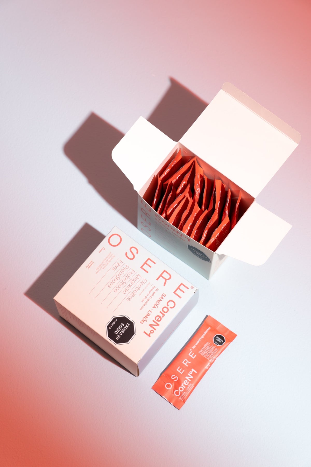 Caja abierta de OSERE CoreN°1 mostrando los sachets rojos en su interior, junto a un sachet suelto